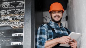 Ein Elektroniker der in einem Serviceraum ein Tablet bedient