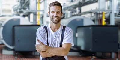 Ein Mann in Arbeitskleidung mit verschraenkten Armen